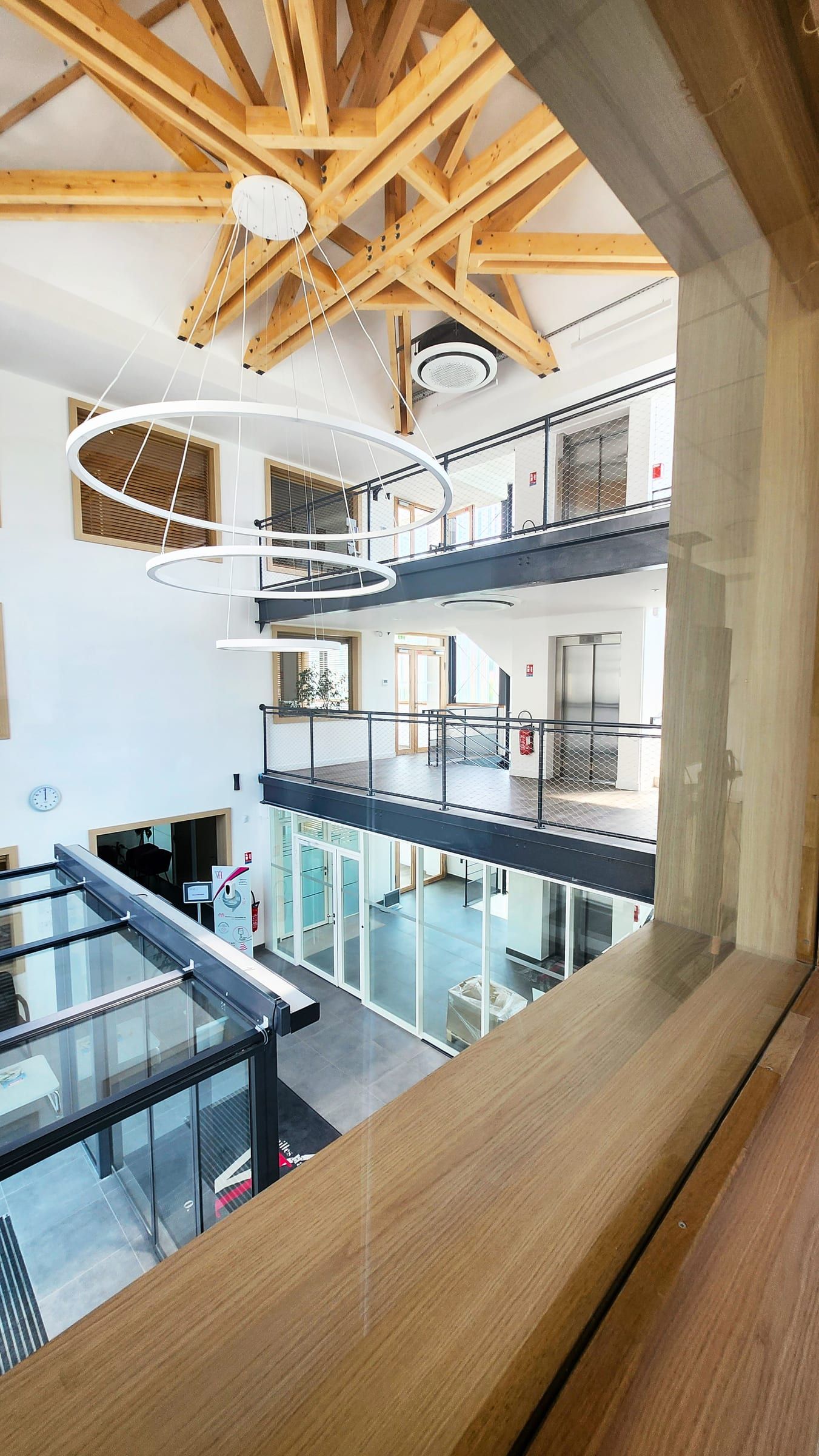 Atrium central avec charpente bois et coursives vitrées