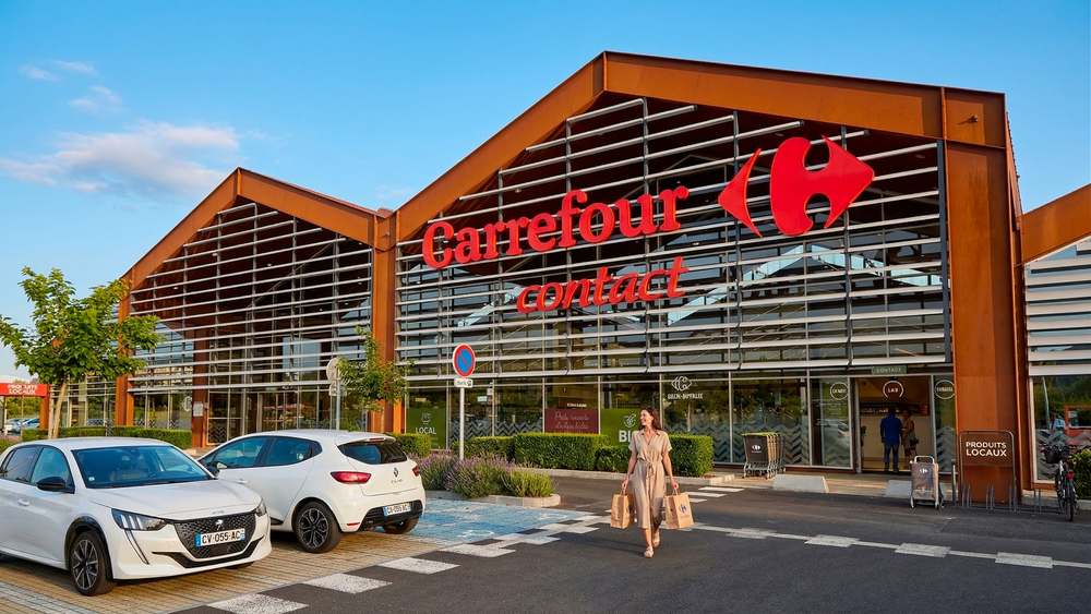 Façade du centre commercial sous ses toitures en sheds, bardage métallique cuivré