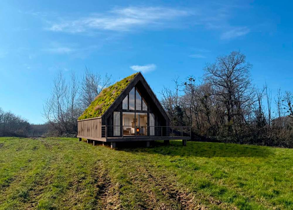 Un lodge en bois à toiture végétalisée dans la prairie